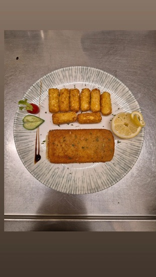 Paniertes Gericht mit goldbrauner Beilage und Zitrone